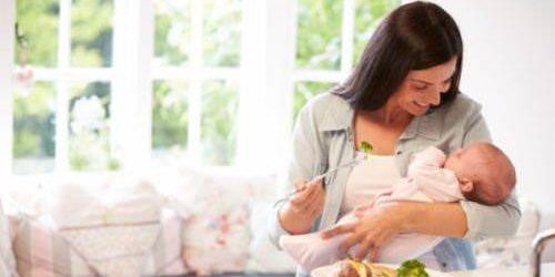 Mãe tendo uma dieta pós-parto saudável, segurando seu bebê.
