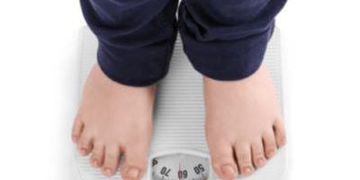 Criança com obesidade infantil, se pesando.